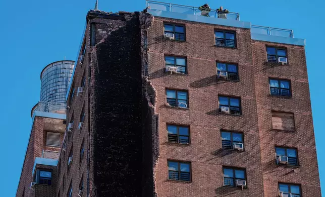 Firefighters stand on the roof of a building that partially collapsed in the Bronx borough of New York, Wednesday, Oct. 1, 2025. (AP Photo/Eduardo Munoz Alvarez)