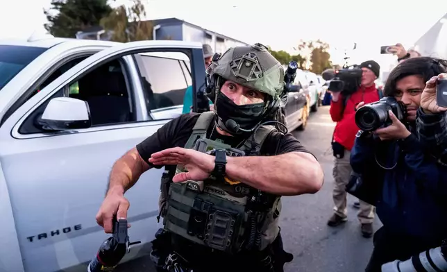 A U.S. Border Patrol officer tries to clear protesters while entering Coast Guard Base Alameda on Thursday, Oct. 23, 2025, in Oakland, Calif. (AP Photo/Noah Berger)