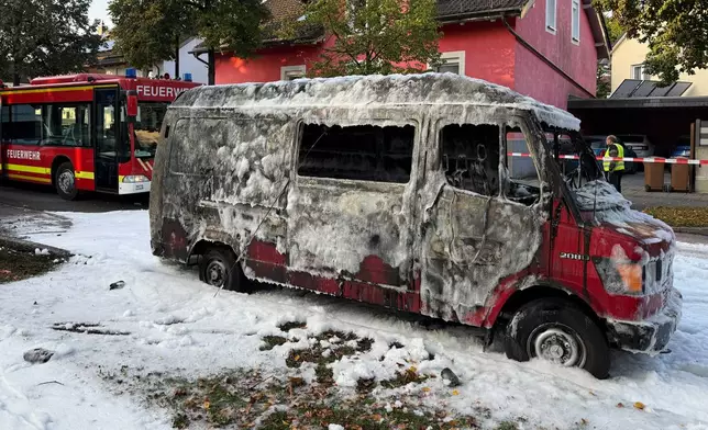 A burned van is covered by extinguishing foam after a fire in Munich, Germany, Wednesday, Oct. 1, 2025. (Roland Freund/dpa via AP)