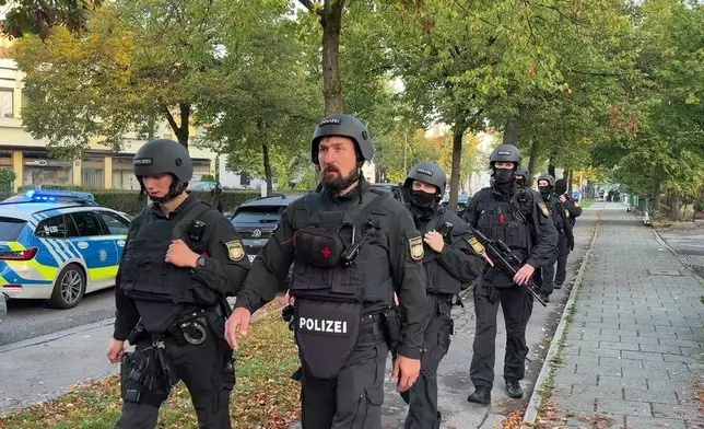 Police officers walk along a footpath after a fire in a detached house in Munich, Germany, Wednesday, Oct. 1, 2025. (Roland Freund/dpa via AP)