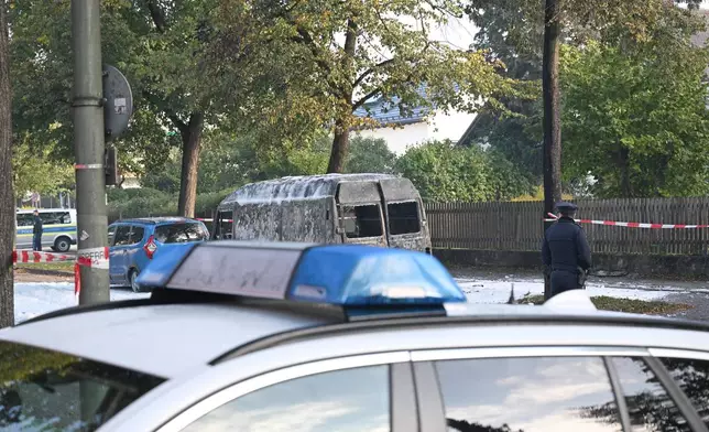 A police car stands in front of a burned van after a fire in Munich, Germany, Wednesday, Oct. 1, 2025. (Roland Freund/dpa via AP)