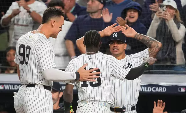 New York Yankees Jazz Chisholm Jr. (13) is congratulated by teammates after scoring the go-ahead run against the Boston Red Sox during the eighth inning of Game 2 of an American League wild-card baseball playoff series, Wednesday, Oct. 1, 2025, in New York. (AP Photo/Yuki Iwamura)