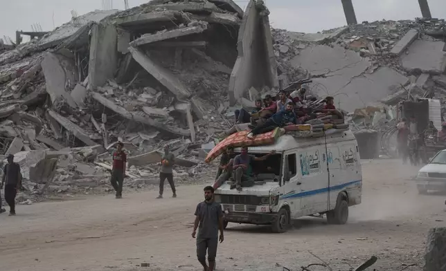 Displaced Palestinians ride on a van loaded with their belongings amid rubble in Gaza City, Sunday, Oct. 12, 2025, after Israel and Hamas agreed to a pause in their war and the release of the remaining hostages. (AP Photo/Abdel Kareem Hana)