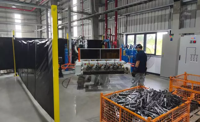 Technician operating a welding cell on the Komaspec Vietnam factory floor.