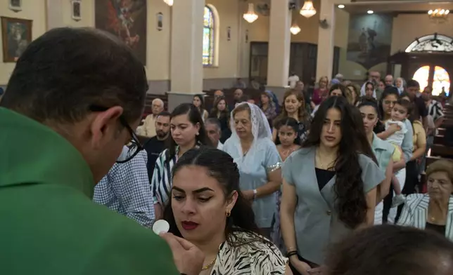Catholic parish priest Bashar Fawadleh offers a communion wafer to a faithful during Mass at Christ the Redeemer Church in the West Bank village of Taybeh, Sept. 28, 2025. (AP Photo/Leo Correa)