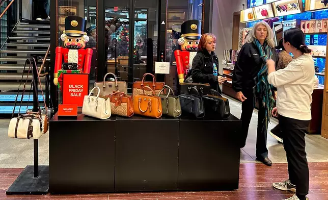 FILE - Shoppers pause near a display of handbags at a Coach store in New York on Sunday, Nov. 19, 2023. (AP Photo/Anne D'Innocenzio, File)