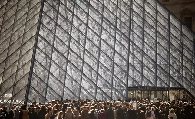 Visitors queue outside of the Louvre museum, Sunday, Oct. 26, 2025 in Paris. The Paris prosecutor said that a number of suspects have been arrested over the theft of crown jewels from Paris' Louvre museum last weekend. (AP Photo/Thomas Padilla)