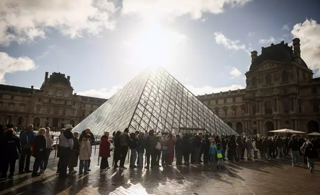 Visitors queue outside the Louvre museum, one week after the robbery, Sunday, Oct. 26, 2025 in Paris. The Paris prosecutor said on Sunday that a number of suspects have been arrested over the theft of crown jewels from Paris' Louvre museum last weekend. (AP Photo/Thomas Padilla)