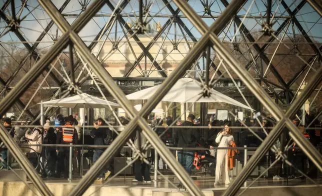 Visitors queue outside the Louvre museum, one week after the robbery, Sunday, Oct. 26, 2025 in Paris. The Paris prosecutor said on Sunday that a number of suspects have been arrested over the theft of crown jewels from Paris' Louvre museum last weekend. (AP Photo/Thomas Padilla)