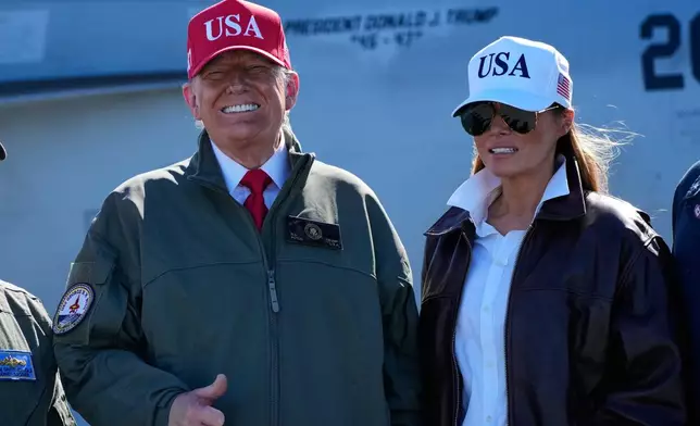 President Donald Trump and first lady Melania Trump pose in front of a F/A-18E fighter jet with President Donald Trump's name on it, as part of the Navy's 250th anniversary celebration, aboard the USS George H.W. Bush aircraft carrier in the Atlantic Ocean off the coast of Norfolk, Va., Sunday, Oct. 5, 2025. (AP Photo/Alex Brandon)