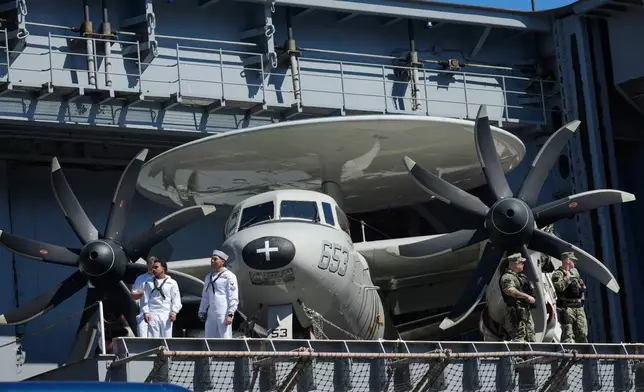 Sailors stand near a E-2 Hawkeye before President Donald Trump arrives to speak during a celebration for the 250th anniversary of the U.S. Navy aboard the USS Harry S. Truman at Naval Station Norfolk, Sunday Oct. 5, 2025 in Norfolk, Va. (AP Photo/Steve Helber)