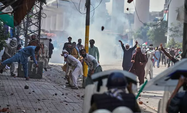 Supporters of Islamist party 'Tehreek-e-Labbaik Pakistan' throw stones toward police during clashes ahead of their pro-Palestinian march toward capital Islamabad, in Lahore, Pakistan, Friday, Oct. 10, 2025. (AP Photo/K.M. Chaudary)