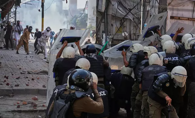 Supporters of Islamist party 'Tehreek-e-Labbaik Pakistan' throw stones toward police who take cover behind shields during clashes ahead of their pro-Palestinian march toward capital Islamabad, in Lahore, Pakistan, Friday, Oct. 10, 2025. (AP Photo/K.M. Chaudary)