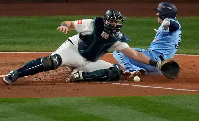 Toronto Blue Jays' Myles Straw scores on a single by Andrés Giménez during the eighth inning in Game 4 of baseball's American League Championship Series as Seattle Mariners catcher Cal Raleigh reaches for the throw, Thursday, Oct. 16, 2025, in Seattle. (AP Photo/David J. Phillip)