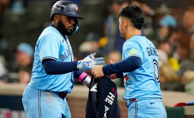 Toronto Blue Jays' Vladimir Guerrero Jr., left, celebrates after his solo home run with teammate Andrés Giménez, right, during the seventh inning of Game 4 of baseball's American League Championship Series against the Seattle Mariners in Seattle, Thursday, Oct. 16, 2025. (Frank Gunn/The Canadian Press via AP)