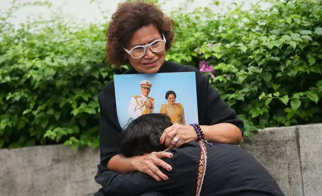 Thai people mourning as they hold the portrait of Thailand Queen Mother Sirikit in Bangkok, Thailand, Saturday, Oct. 25, 2025. (AP Photo/Sakchai Lalit)
