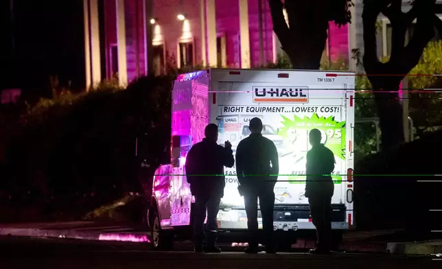 Police officers examine a U-Haul truck involved in a shooting at the entrance to Coast Guard Base Alameda, according to an officer at the scene, on Friday, Oct. 24, 2025, in Oakland, Calif. (AP Photo/Noah Berger)