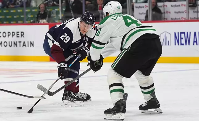 Dallas Stars defenseman Ilya Lyubushkin, front, knocks the puck away from Colorado Avalanche center Nathan MacKinnon in the first period of an NHL hockey game Saturday, Oct. 11, 2025, in Denver. (AP Photo/David Zalubowski)