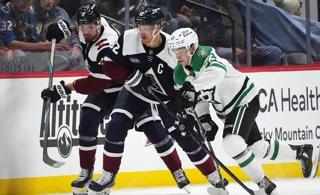Dallas Stars center Wyatt Johnston, right, pursues the puck with Colorado Avalanche left wing Gabriel Landeskog, center, and right wing Valeri Nichushkin in the second period of an NHL hockey game against the Dallas Stars, Saturday, Oct. 11, 2025, in Denver. (AP Photo/David Zalubowski)