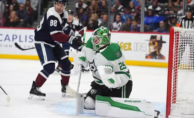 Dallas Stars goaltender Jake Oettinger, front, stops a shot as Colorado Avalanche center Martin Necas covers in the first period of an NHL hockey game Saturday, Oct. 11, 2025, in Denver. (AP Photo/David Zalubowski)
