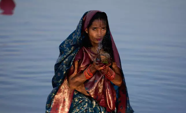 A Hindu devotee performs rituals at sunset on the banks of the Tawi River during Chhath Puja festival in Jammu, India, Monday, Oct. 27, 2025. (AP Photo/Channi Anand)