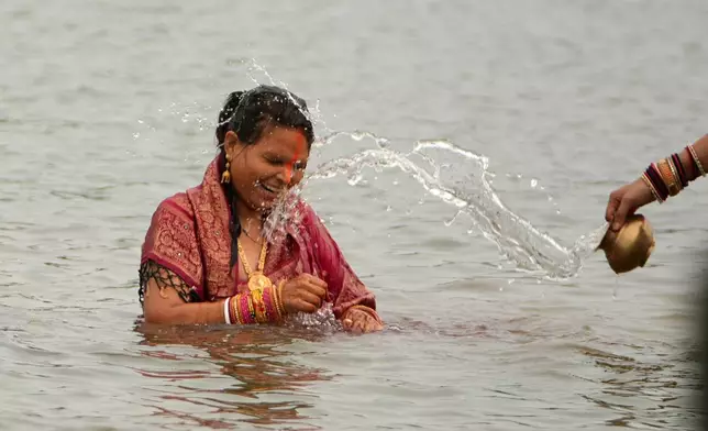 Hindu devotees perform rituals at sunset in the River Sabarmati during Chhath Puja festival in Ahmedabad, India, Monday, Oct. 27, 2025. (AP Photo/Ajit Solanki)