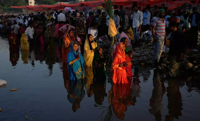Hindu devotees perform rituals at sunset on the banks of the Tawi River during Chhath Puja festival in Jammu, India, Monday, Oct. 27, 2025.(AP Photo/Channi Anand)