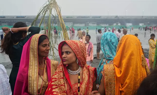 Women wait to perform prayers during Chhath festival on the banks of the river Yamuna, in New Delhi, India, Monday, Oct. 27, 2025. (AP Photo/Manish Swarup)