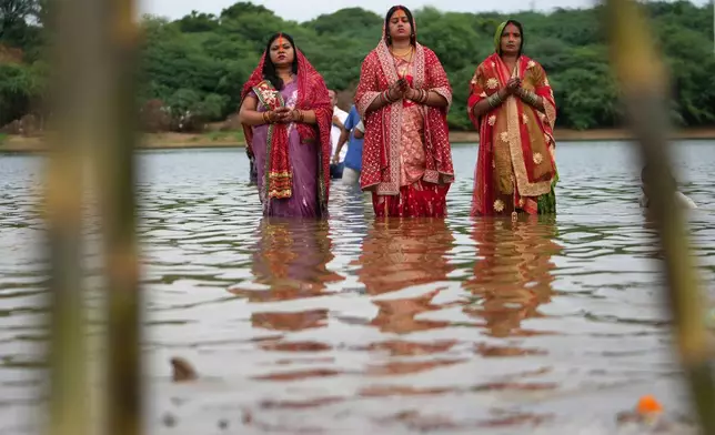 Hindu devotees perform rituals at sunset in the River Sabarmati during Chhath Puja festival in Ahmedabad, India, Monday, Oct. 27, 2025. (AP Photo/Ajit Solanki)