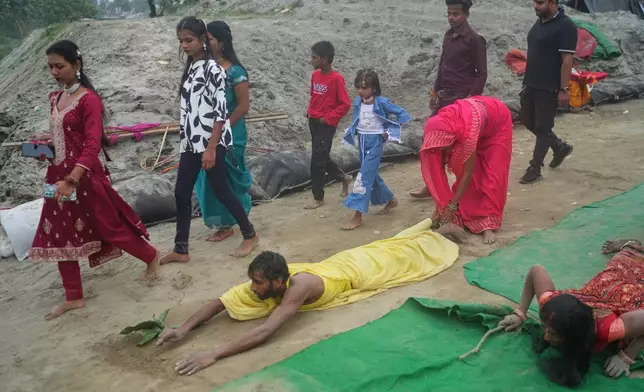 A devotee prostrates and performs rituals on his way to the River Yamuna during the Chhath festival, which is celebrated for the well-being and prosperity of one's family, in New Delhi, India, Monday, Oct. 27, 2025. (AP Photo/Manish Swarup)