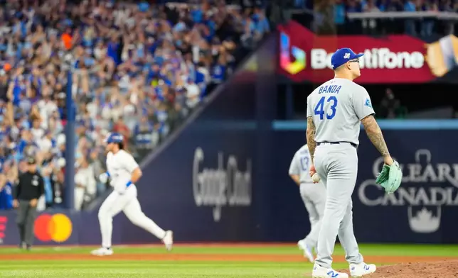 Los Angeles Dodgers pitcher Anthony Banda (43) reacts as Toronto Blue Jays' Addison Barger, back left, rounds the bases after hitting a grand slam during the sixth inning of Game 1 of baseball's World Series in Toronto, Friday, Oct. 24, 2025. (Frank Gunn/The Canadian Press via AP)