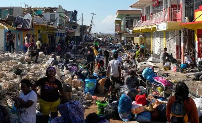 Residents gather amid debris in the aftermath of Hurricane Melissa on a street in Black River, Jamaica, Thursday, Oct. 30, 2025. (AP Photo/Matias Delacroix)