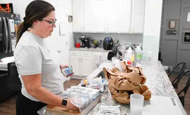 Jennifer Bittner unloads a case of PediaSure at her home on Wednesday, Oct. 29, 2025, in Pflugerville, Texas. (AP Photo/Jack Myer)
