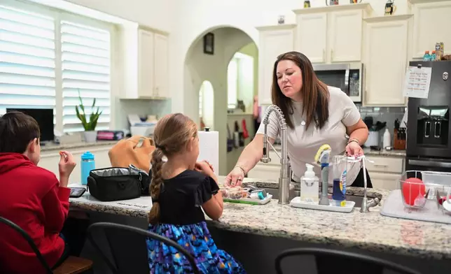 Jennifer Bittner serves lunch to her children at her home on Wednesday, Oct. 29, 2025, in Pflugerville, Texas. Bittner worries the government shutdown will affect her husband's Army salary, and thus their ability to afford their children's healthcare costs. (AP Photo/Jack Myer)