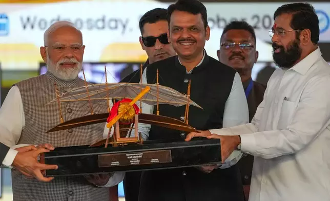 Maharashtra Deputy Chief Minister Eknath Shinde, right, and Maharashtra Chief Minister Devendra Fadnavis, centre, present a replica of a vintage plane to Indian Prime Minister Narendra Modi, left, during the inauguration ceremony of the Navi Mumbai International Airport in Navi Mumbai, India, Wednesday, Oct. 8, 2025. (AP Photo/Rafiq Maqbool)