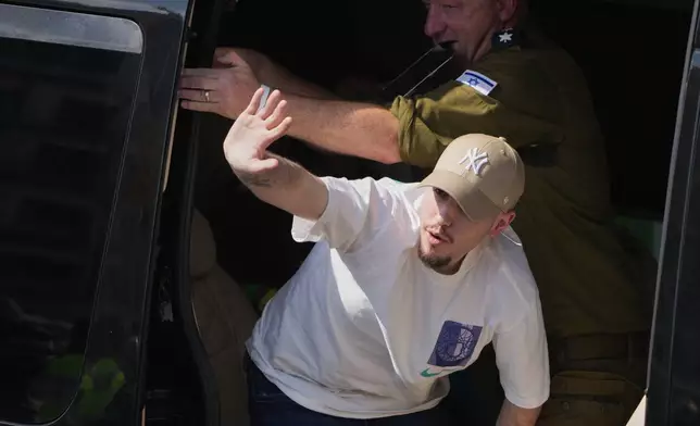 Freed Israeli hostage Eitan Mor gestures from a van as he arrives at Beilinson hospital in Petah Tikva, Israel, after he was released from Hamas captivity in the Gaza Stripl, Monday, Oct. 13, 2025. (AP Photo/Ariel Schalit)