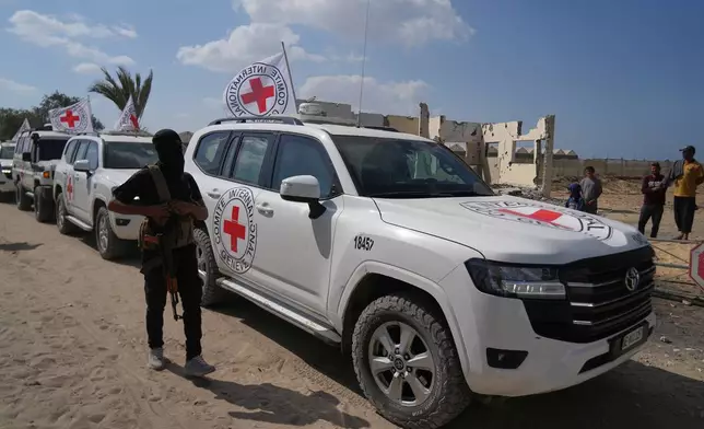 A masked Hamas gunman stands next to Red Cross vehicles arriving for the handover of Israeli hostages by Hamas, in Khan Younis, southern Gaza Strip, Monday, Oct. 13, 2025. (AP Photo/Abdel Kareem Hana)