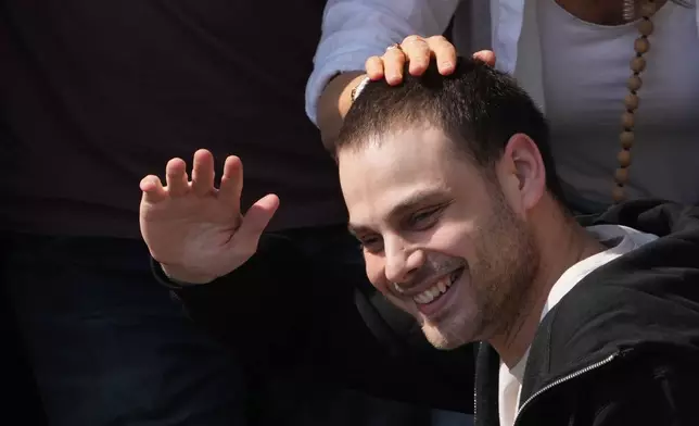 Freed Israeli hostage Alon Ohel gestures from a van as he arrives at Beilinson hospital in Petah Tikva, Israel, after he was released from Hamas captivity in the Gaza Stripl, Monday, Oct. 13, 2025. (AP Photo/Ariel Schalit)