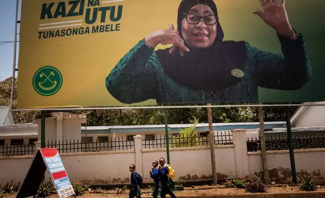 School children walk past a billboard for Tanzanian presidential candidate Samia Suluhu Hassan, of the ruling Chama Cha Mapinduzi party, in Arusha, Tanzania, Oct. 8, 2025. (AP Photo)