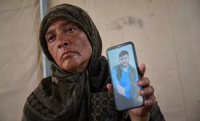 Fadwa al-Ghalban holds a cellphone showing a photo of her son, Mosaab, at her tent in Muwasi, along Gaza's southern coast, Oct. 3, 2025. She has had no word from him since July, when his cousins last saw him near their house as an Israeli strike destroyed it in the southern town of Maan. (AP Photo/Jehad Alshrafi)