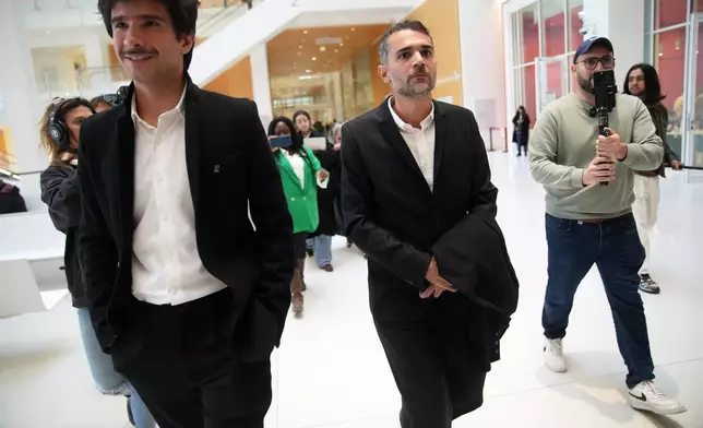Activist Juan Branco , left, and defendant Aurelien Poirson-Atlan, known as Zoe Sagan on social media, leave for break as ten people go on trial accused of cyberbullying Brigitte Macron after they allegedly made "malicious" comments online spreading claims that President Emmanuel Macron's wife is a man, Tuesday, Oct. 28, 2025 in Paris. (AP Photo/Christophe Ena)
