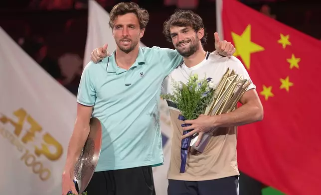 Winner Valentin Vacherot of Monaco, right, and Arthur Rinderknech of France, embrace on the winners podium after the final of the Shanghai Masters tennis tournament at Qizhong Forest Sports City Tennis Center, in Shanghai, China, Sunday, Oct. 12, 2025. (AP Photo/Andy Wong)