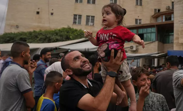 Palestinians celebrate following the announcement that Israel and Hamas have agreed to the first phase of a peace plan to pause the fighting, outside Al-Aqsa Hospital in Deir al-Balah, central Gaza Strip, Thursday, Oct. 9, 2025. (AP Photo/Abdel Kareem Hana)