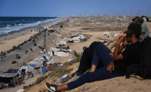 Displaced Palestinians gather on the coastal road near Wadi Gaza in the central Gaza Strip, Thursday, Oct. 9, 2025, during an attempt to return to Gaza City after the announcement that Israel and Hamas had agreed to the first phase of a peace plan to pause the fighting. (AP Photo/Abdel Kareem Hana)