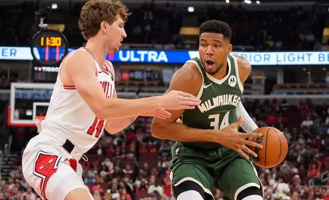 Chicago Bulls forward Matas Buzelis, left, defends against Milwaukee Bucks forward Giannis Antetokounmpo, right, during the first half of a preseason NBA basketball game Sunday, Oct. 12, 2025, in Chicago. (AP Photo/David Banks)