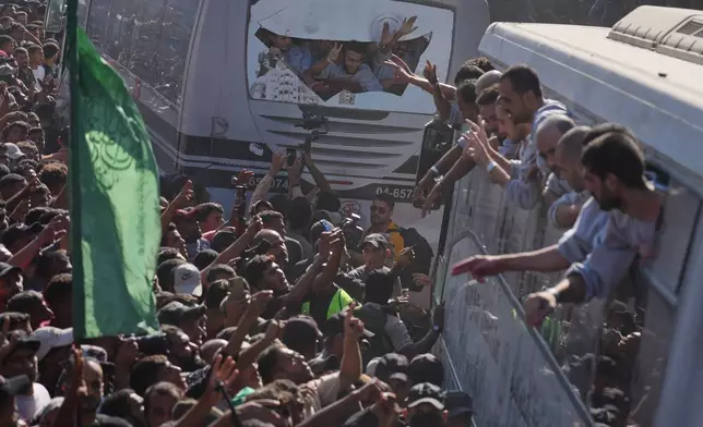 People gather to greet freed Palestinian prisoners arriving on buses in the Gaza Strip after their release from Israeli jails under a ceasefire agreement between Hamas and Israel, outside Nasser Hospital in Khan Younis, southern Gaza Strip, Monday, Oct. 13, 2025. (AP Photo/Jehad Alshrafi)