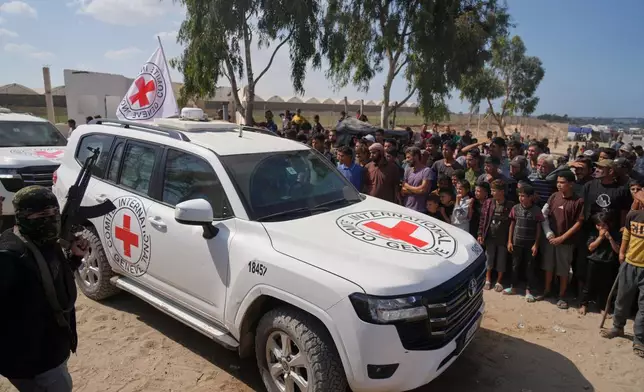 ICRC vehicles carrying released Israeli hostages make their way through groups of Palestinians and Hamas gunmen on their way to the Israeli border, in Khan Younis, southern Gaza Strip, Monday, Oct. 13, 2025. (AP Photo/Jehad Alshrafi)
