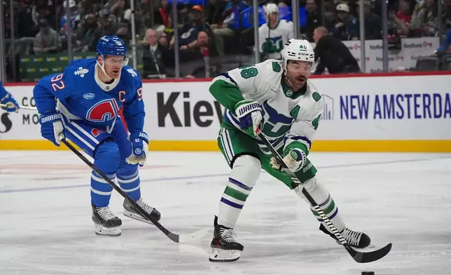 Carolina Hurricanes left wing Jordan Martinook, right, drives to the net past Colorado Avalanche left wing Gabriel Landeskog in the second period of an NHL hockey game Thursday, Oct. 23, 2025, in Denver. (AP Photo/David Zalubowski)