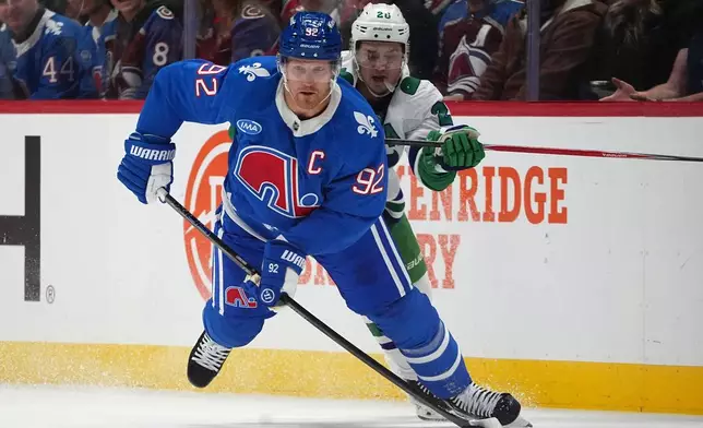 Colorado Avalanche left wing Gabriel Landeskog, front, collects the puck as Carolina Hurricanes center Sebastian Aho defends in the second period of an NHL hockey game Thursday, Oct. 23, 2025, in Denver. (AP Photo/David Zalubowski)