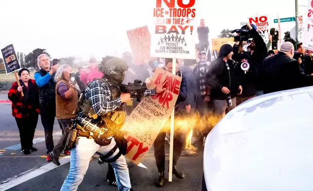 A person pushes a protester blocking a caravan of U.S. Customs and Border Protection personnel trying to enter Coast Guard Base Alameda on Thursday, Oct. 23, 2025, in Oakland, Calif. (AP Photo/Noah Berger)